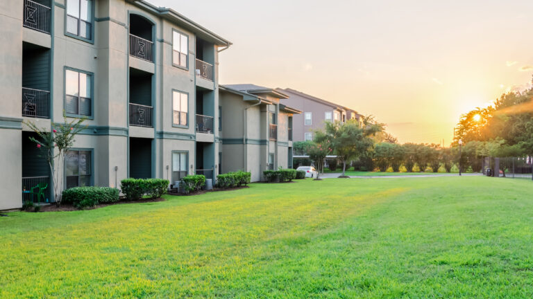 View from grassy backyard of a typical apartment complex building in suburban area at Humble, Texas, US. Sunset with warm light. Panorama style.